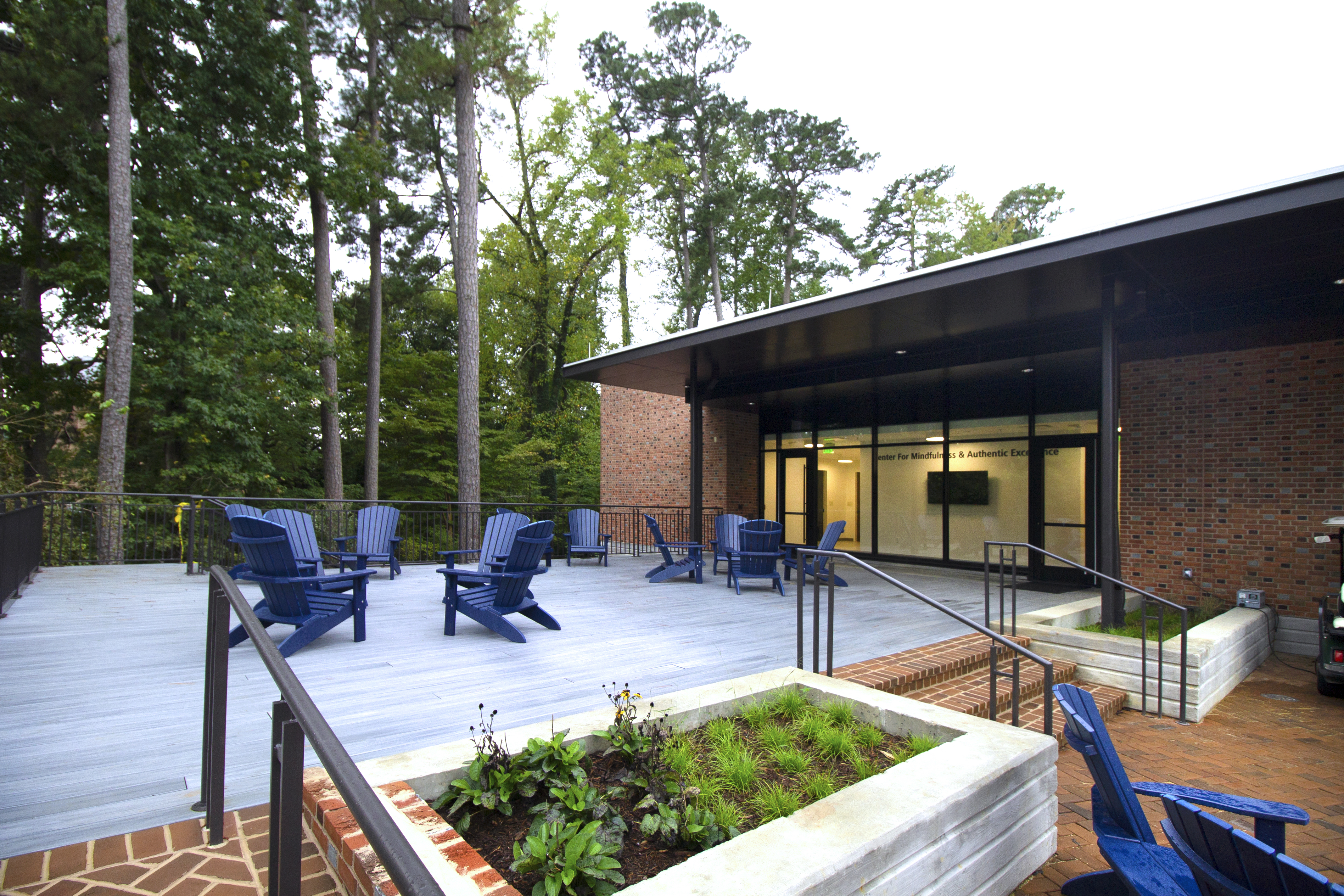 McLeod Tyler Wellness Center’s Outdoor patio set up with multiple outdoor seating arrangements, views of surrounding natural landscape, and outdoor lighting design by Henry Adams MEP engineering firm that promotes light pollution reduction 