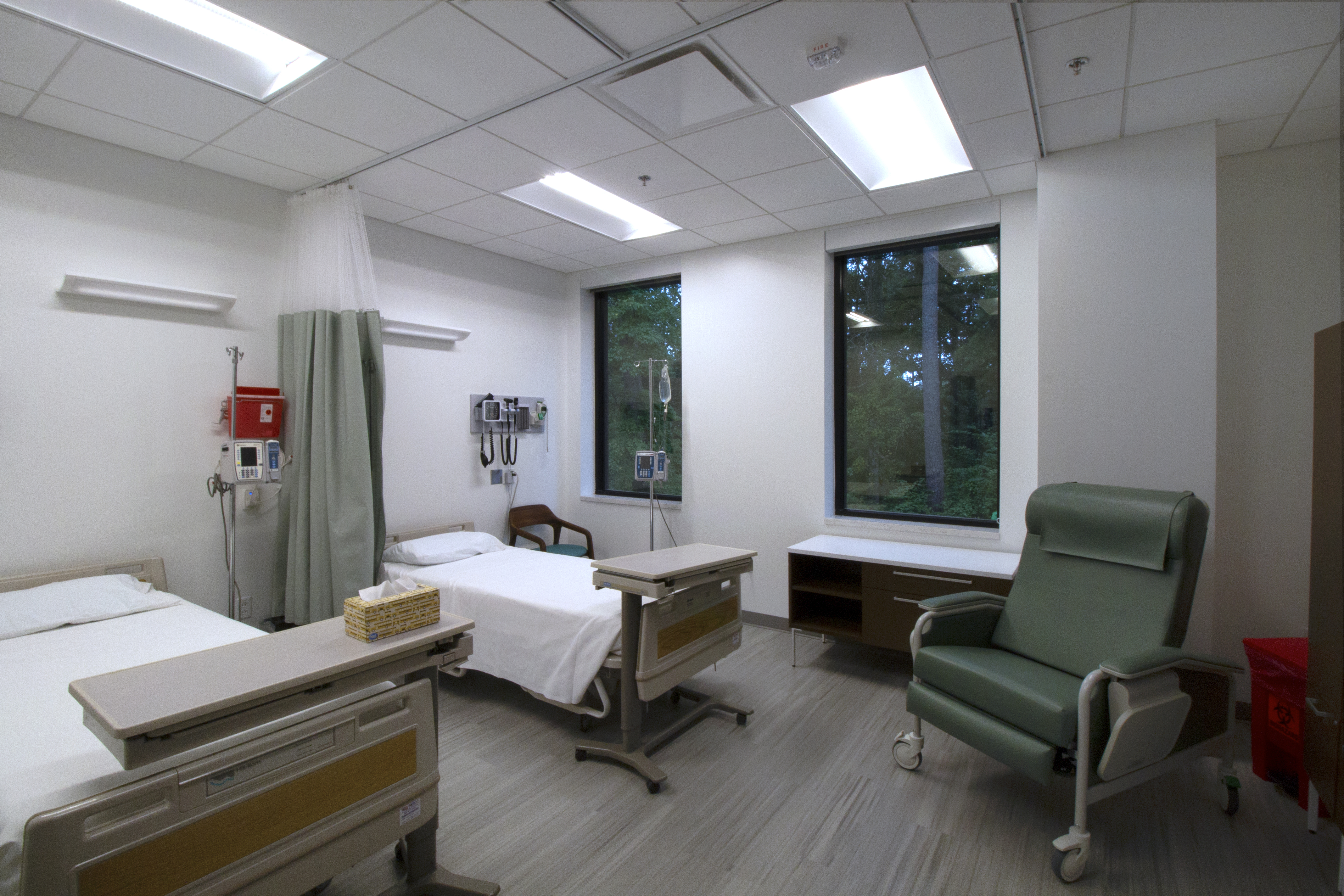 : Recovery room in the McLeod Tyler Wellness Center containing hospital beds next to two large windows, medical equipment on the walls and a curtain dividing the room 