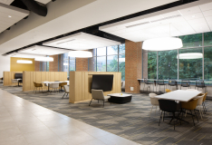 Interior photo of the Towson University Union building. The photo shows student lounging/meeting spaces complete with long white tables, an assortment of colorful chairs, televisions, and modern cylindrical lighting overhead.